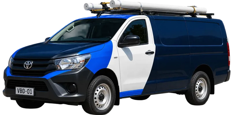 A licensed Five Dock plumbing van loaded with pipe on the roof rack